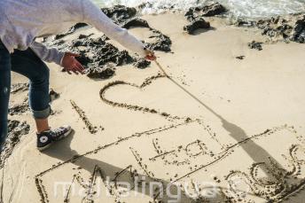 Étudiant écrivant I LOVE Maltalingua dans le sable