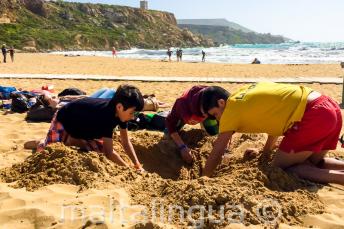 Chef de groupe et étudiants faisant un trou dans le sable à la plage