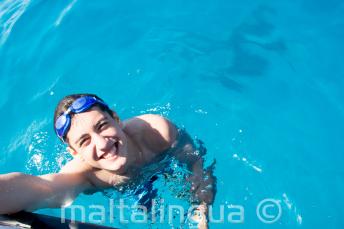 Un étudiant nageant prêt du bateau à Comino.